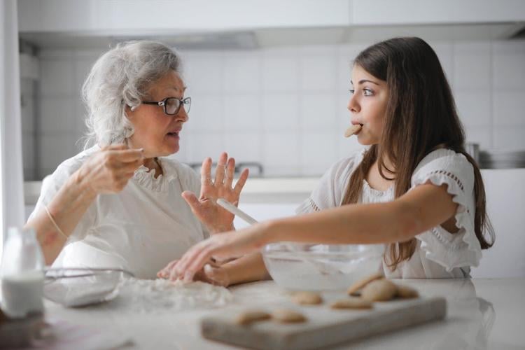 An aging woman and her granddaughter bake cookies
