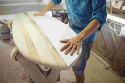 man-making-surfboard giving Beginners a Guide To Buying Your First Surfboard