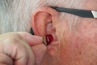 Man inserts modern hearing aid into his ear