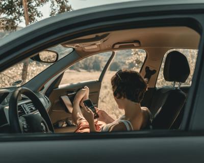 Woman sits in broken down car waiting for roadside assistance