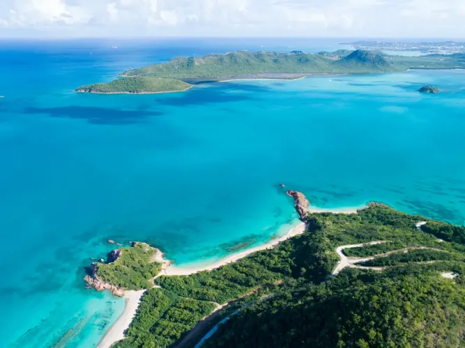 Aerial view of a beach and green hillside at Pearns Point, Antigua, overlooking turquoise water.