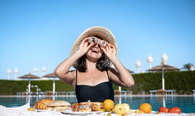 Young woman rejoices at delicious food near the pool. The concept of vacation and recreation in a warm country.