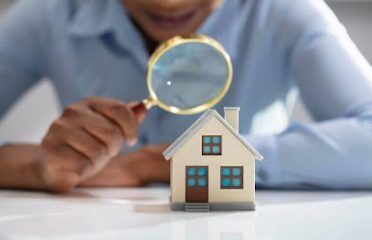 Person inspects miniature house to demonstrate the significance of a comprehensive home inspection report