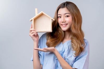 Young woman holds replica of house she wants to purchase after college