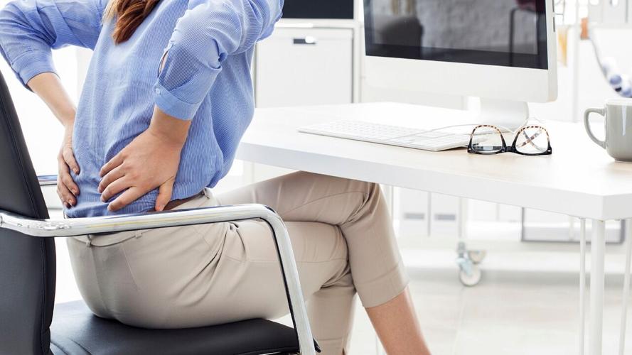 Woman clutches at the back pain caused by her workspace