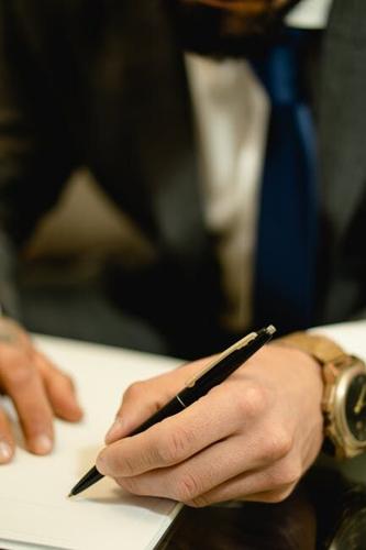 clos up photo of a person hand signing a paper