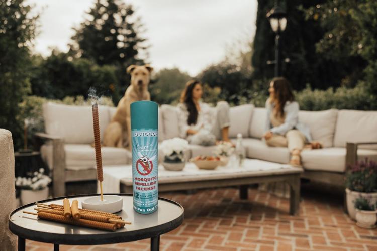 people outside a dusk with Frank;s Skeeter Sticks lit on the table to repel mosquitos