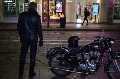 motorcycle parked with a stylish man standing next to it.