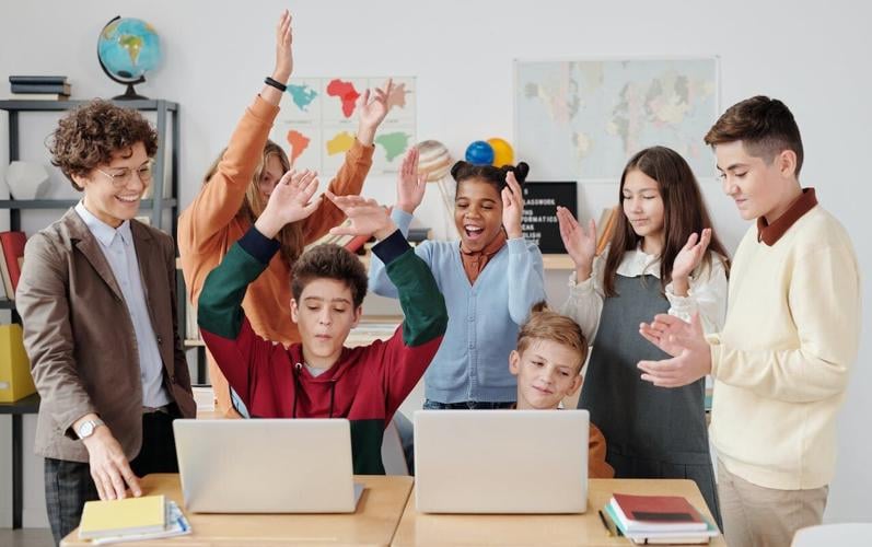 Kids play a learning game in the classroom using laptops