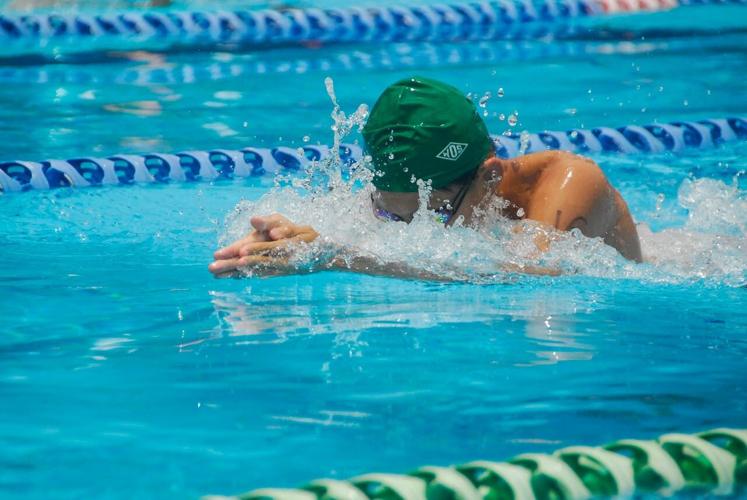A person swims in a lane in a pool for exercise