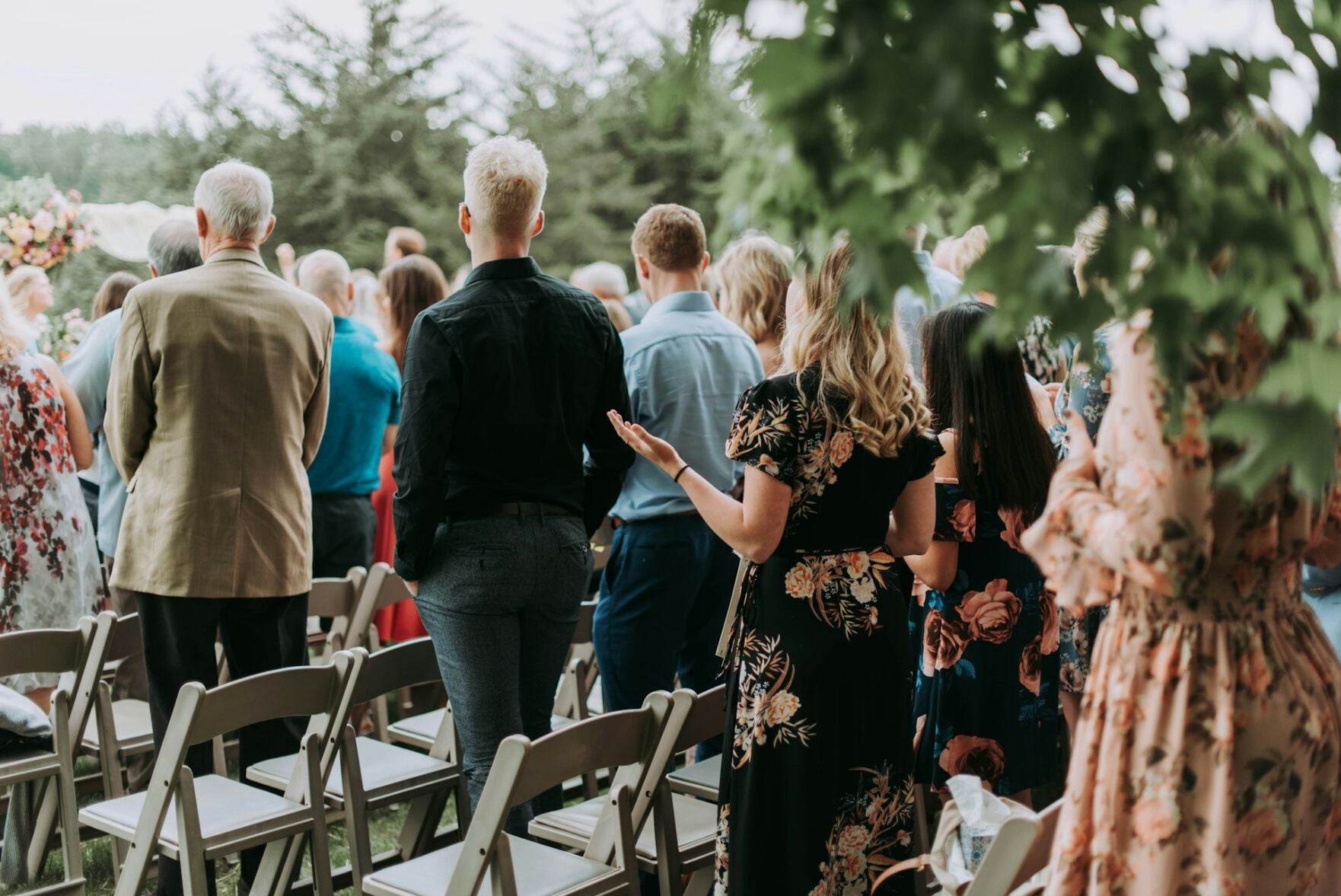 Wedding guests stand during the ceremony, showing off their outfits