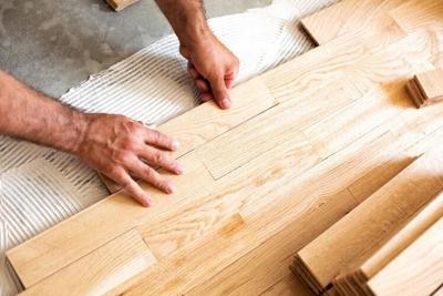 Person lays down wood flooring in a popular pattern