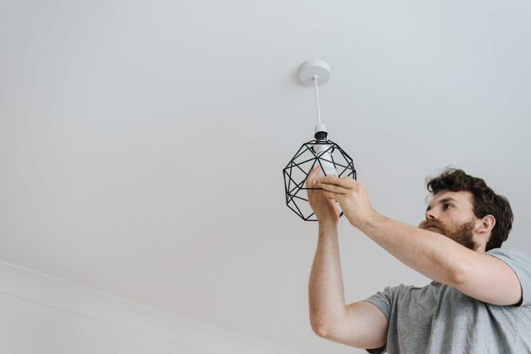 Man practices electrical safety while screwing a lightbulb into a fixture