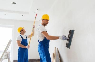Two men paint the internal walls of a commercial space