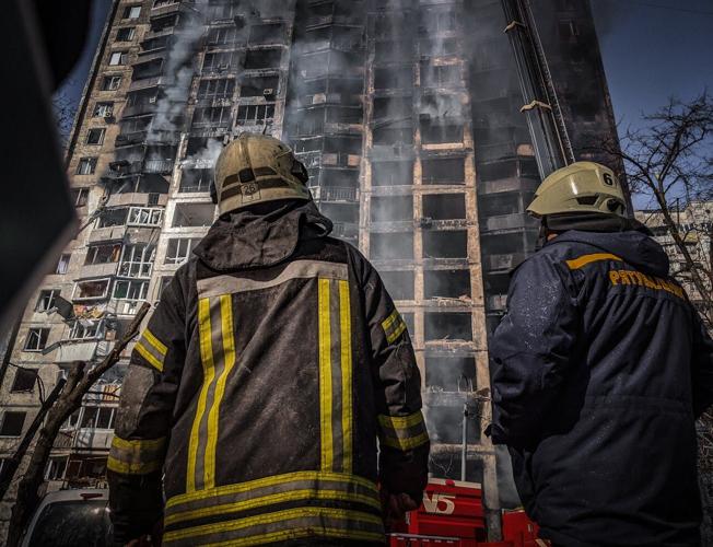 Firefighters look up at a burning building