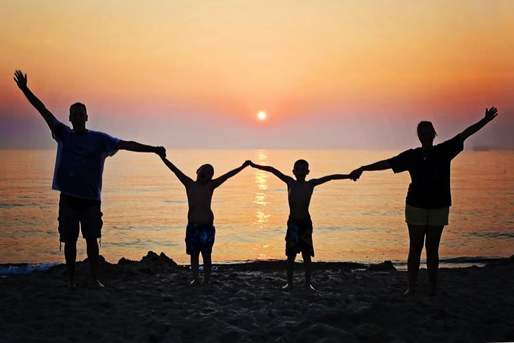 Family hold hands at the beach during weekend connection activity