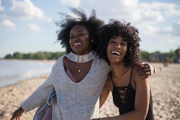 Two happy women pose on the beach, healthy because of their smokeless lifestyle