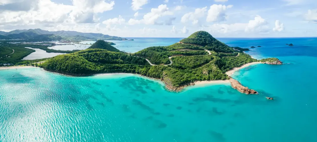 Aerial view of Pearns Point in Antigua surrounded by turquoise Caribbean water and green hills.