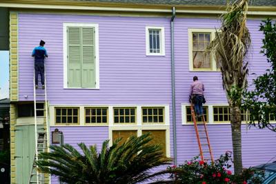 People paint the exterior walls of a house during the summer