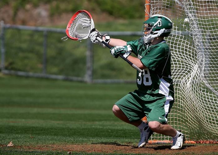 Lacrosse goalie extends stick to catch the ball and protect the goal