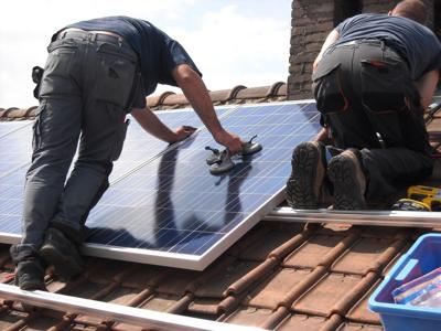 Two men install solar panels on a home's roof