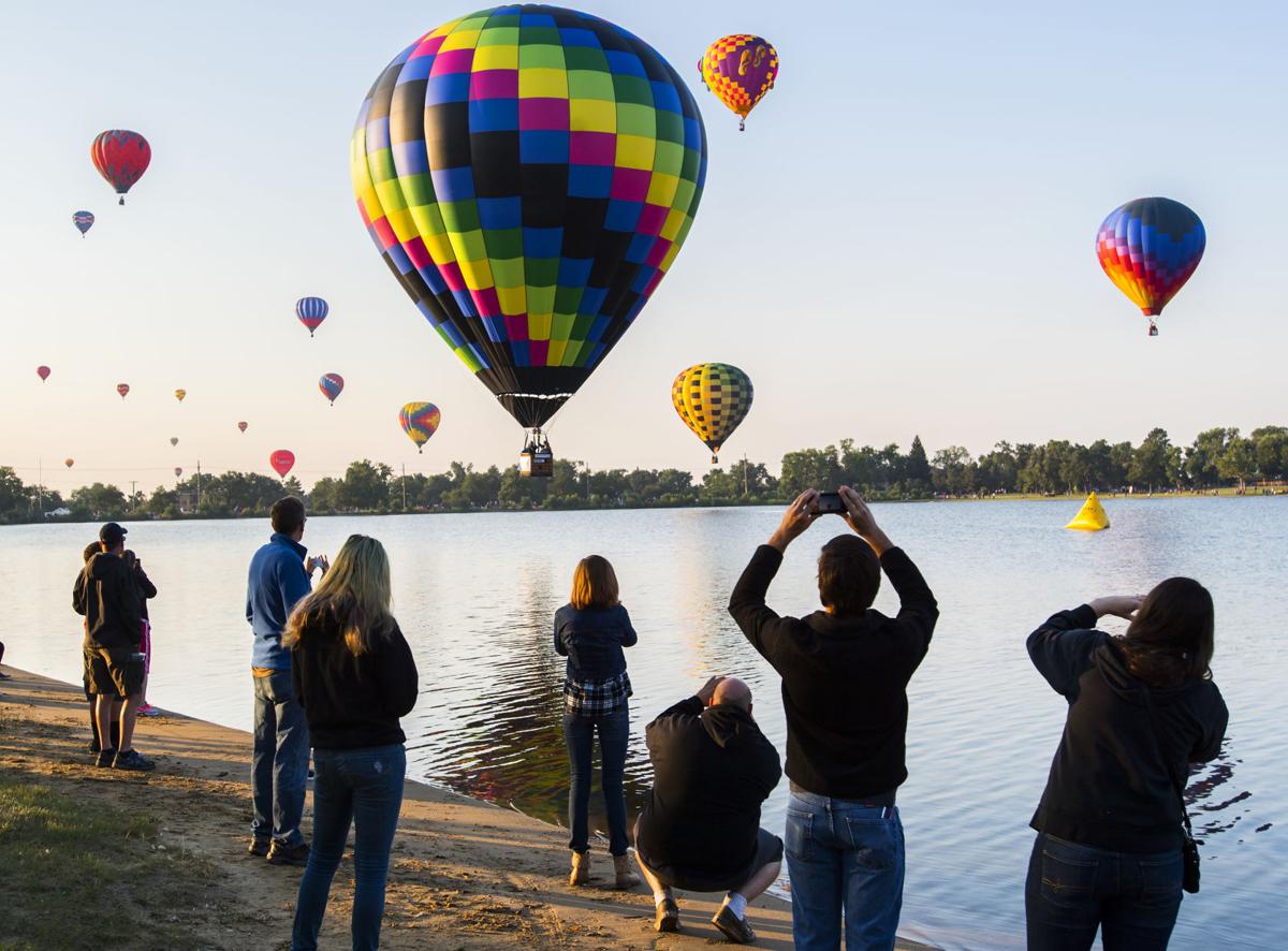 Spectators watch as balloons float over Prospect Lake Saturday, Sept. 2, 2017, during the Colorado Springs Labor Day Lift Off in Memorial Park. The balloon festival runs through Monday morning. (The Gazette, Christian Murdock)