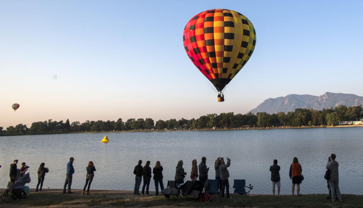 Spectators watch as balloons float over Prospect Lake Saturday, Sept. 2, 2017, during the Colorado Springs Labor Day Lift Off in Memorial Park. The balloon festival runs through Monday morning. (The Gazette, Christian Murdock)