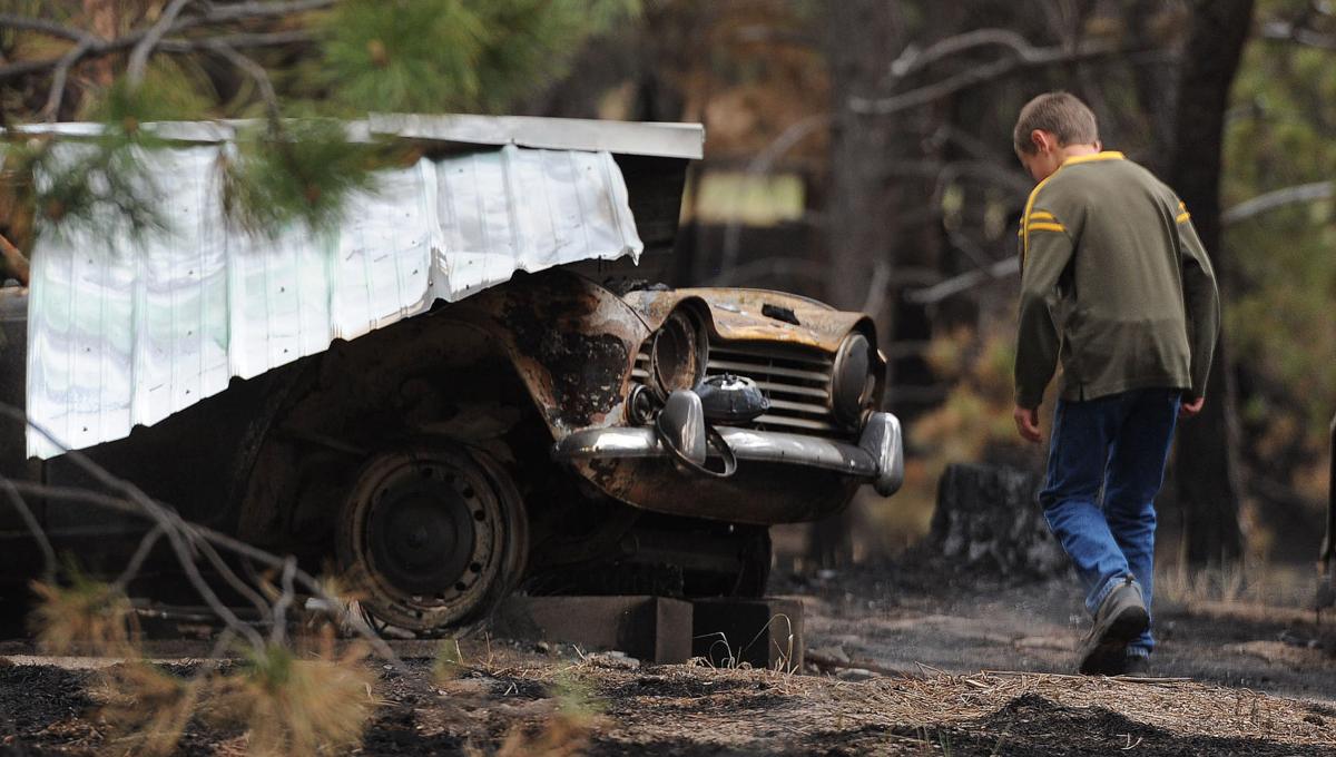 Nathaniel Seay takes a look at a demolished vintage car that belongs to his grandfather, . Nathaniel's grandfather's home burned to the ground in the Black Forest Fire. Homeowners that are north of Burgess Rd. and east of Vollmer Rd. in the Black Forest burn area were able to return to their homes today on Tuesday, June 18, 2013.(Jerilee Bennett/The Gazette)