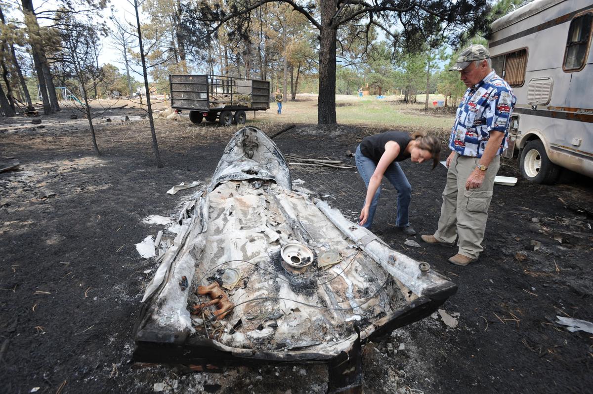 Renee Seay looks at what is left of a boat that belonged to her father, Dick Hoffman (right). Hoffman lost his home in the Black Forest Fire in Colorado . Homeowners that are north of Burgess Rd. and east of Vollmer Rd. in the Black Forest burn area were able to return to their homes today on Tuesday, June 18, 2013.(Jerilee Bennett/The Gazette)