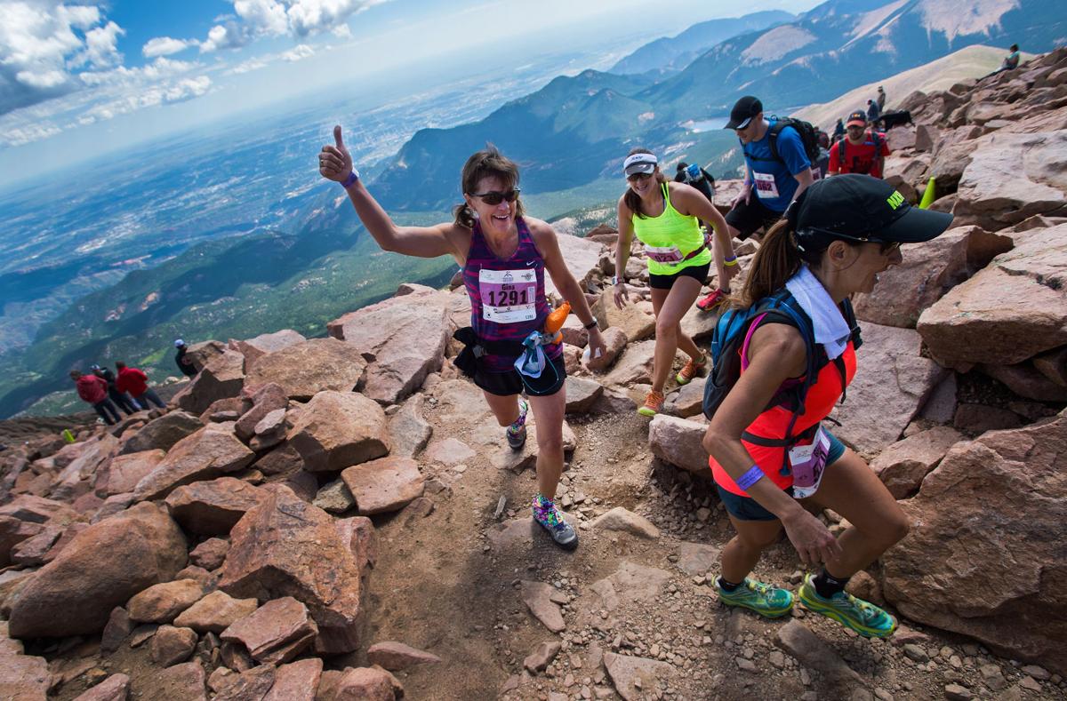 Gina McCutcheon of Colorado Springs celebrates as she turns the final corner to the finish of 2015 Pikes Peak Ascent Saturday, Aug. 15, 2015, on the top of 14,115-foot Pikes Peak. The 13.2-mile race begins in Manitou Springs, Colo., and follows Barr Trail to the top of the mountain. (AP Photo/The Gazette, Christian Murdock)