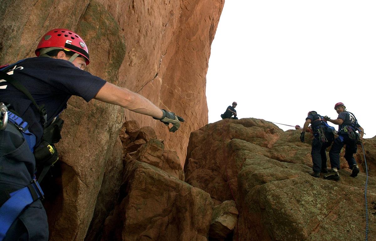 Norm Howard, left, of Engine 5 helps Engine 13's James Mondragon, far right, guide his would-be victim firefighter Rich Renz down a dangerous portion of rock during high-angle rescue training at Garden of the Gods on Monday, Aug. 19, 2002. It's been about an average year of rescue attempts for both stations who hone their skills in the park about every two-weeks. The crews were training in this particular spot on the west side of the Kissing Camels rock formation where a rescue was made earlier this summer. The Gazette, Bryan Oller