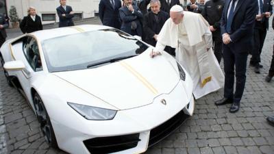 Pope Francis writes on the bonnet of a Lamborghini donated to him by the luxury sports car maker, at the Vatican, Wednesday, Nov. 15, 2017. The car will be auctioned off by Sotheby's, with the proceeds going to charities including one aimed at helping r...