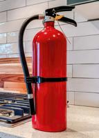 Vertical Fire Extinguisher And Cooktop With Kettle On The Countertop Inside Home Kitchen