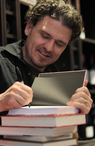 Writer Dave Eggers signs several books for a fan during a book signing at the Book Cellar, Saturday Feb. 2,  2013.