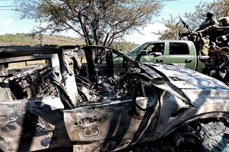 Members of the army onboard a truck are seen next to a burned car used to block roads while Mexican drug lord "El Mencho" tried to flee, near the " Tapalpa Country Club", where he was hiding at the moment of the operation in which he was killed, in Tapa...