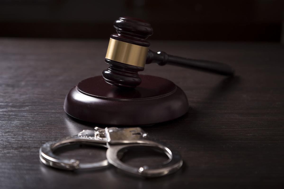 Close up of a judge gavel and handcuffs in a courtroom.