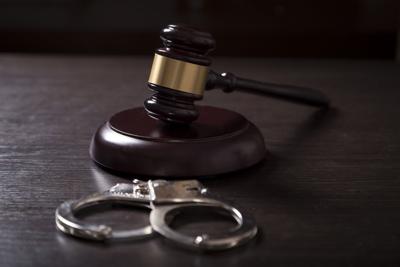 Close up of a judge gavel and handcuffs in a courtroom.