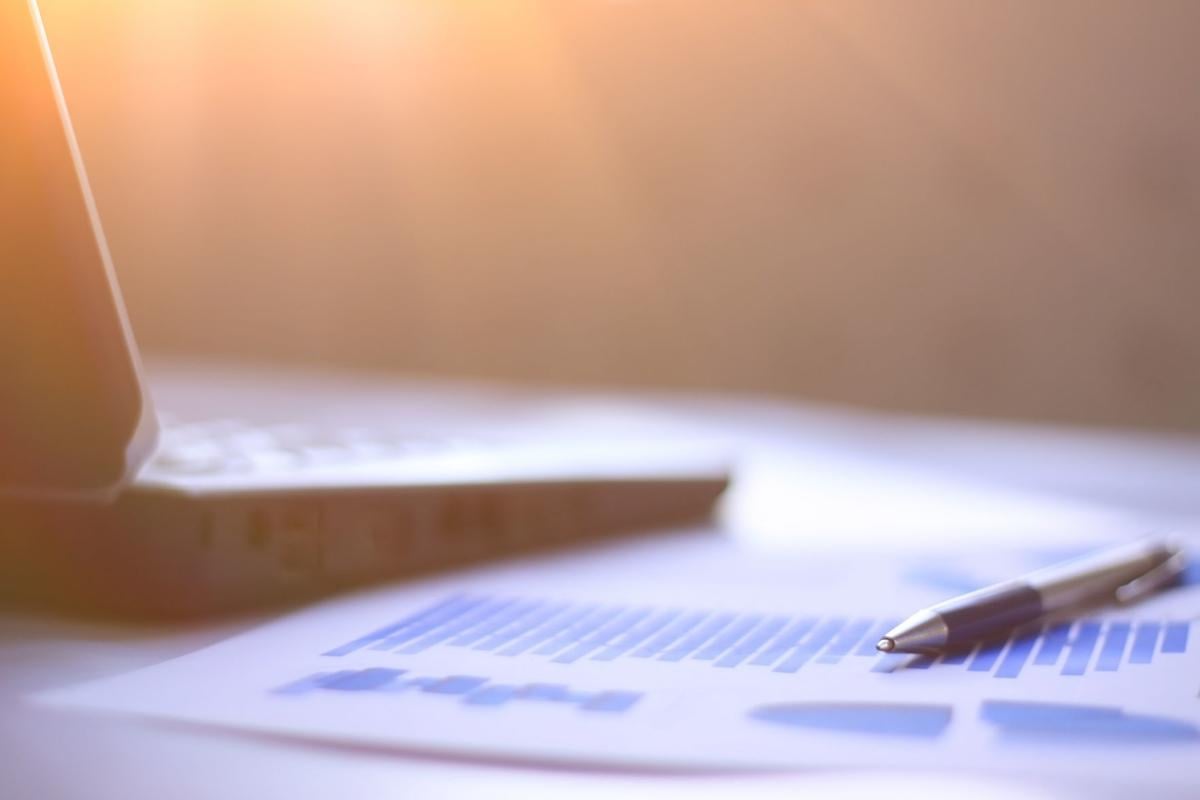 business background: laptop,financial chart and pen on office workplace