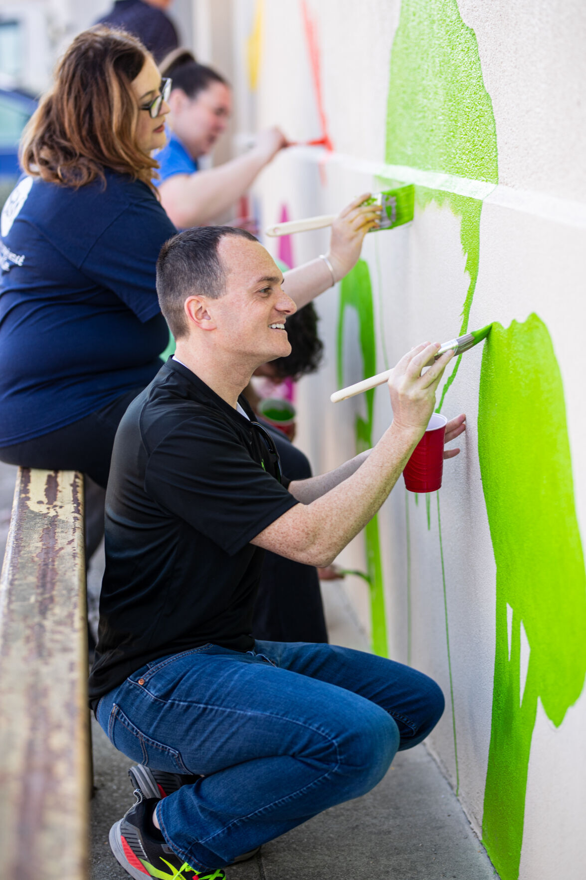 Volunteers paint mural on front of Facing Hunger Foodbank during United
