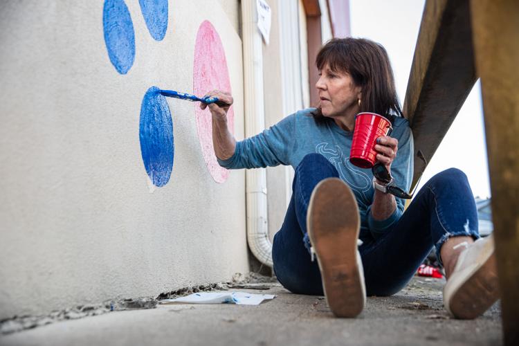 Volunteers paint mural on front of Facing Hunger Foodbank during United