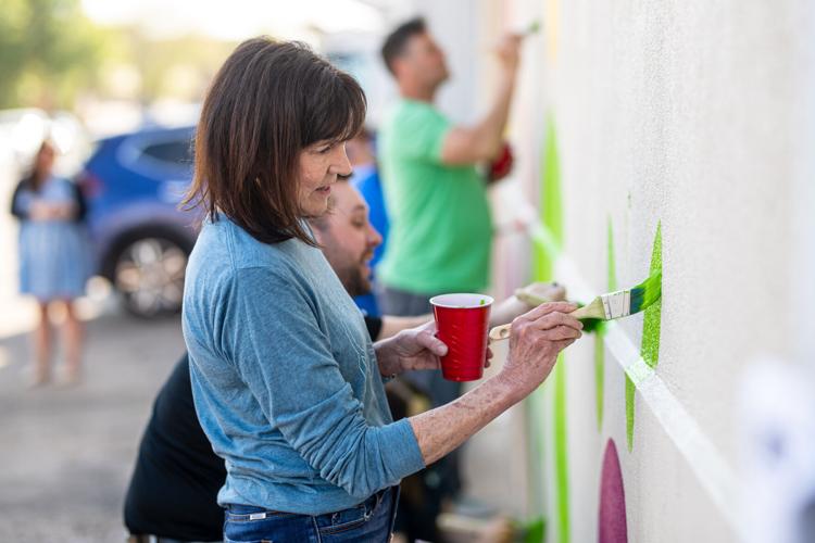 Volunteers paint mural on front of Facing Hunger Foodbank during United