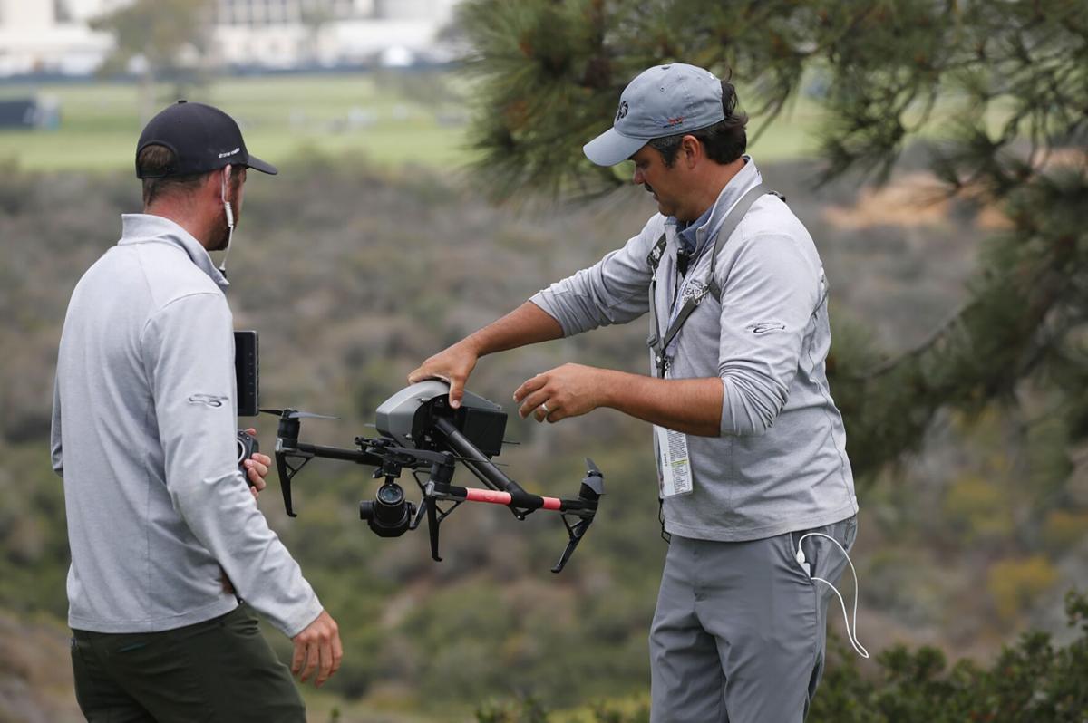 Drone operator Ben McClung picks up a drone used for coverage of the U.S. Open at the Torrey Pines Golf Course on Wednesday, June 16, 2021 in La Jolla, Calif. Tanner Deprin, left, looks on.