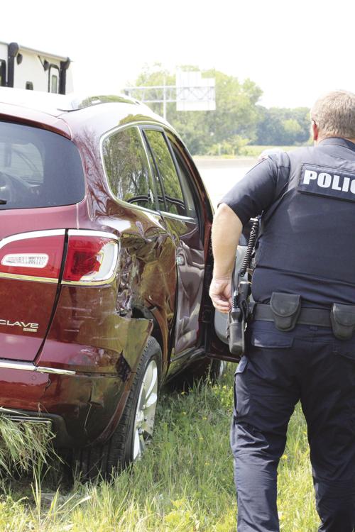 Officer Jack Wilkinson examines damage to Buick Enclave