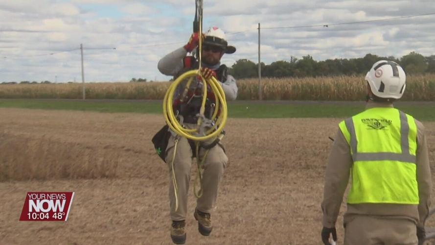 Power line workers soar through the sky hanging from a helicopter in Allen County
