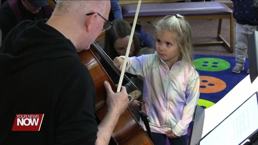 Young children learn about and hear music from string instruments at Symphony Storytime