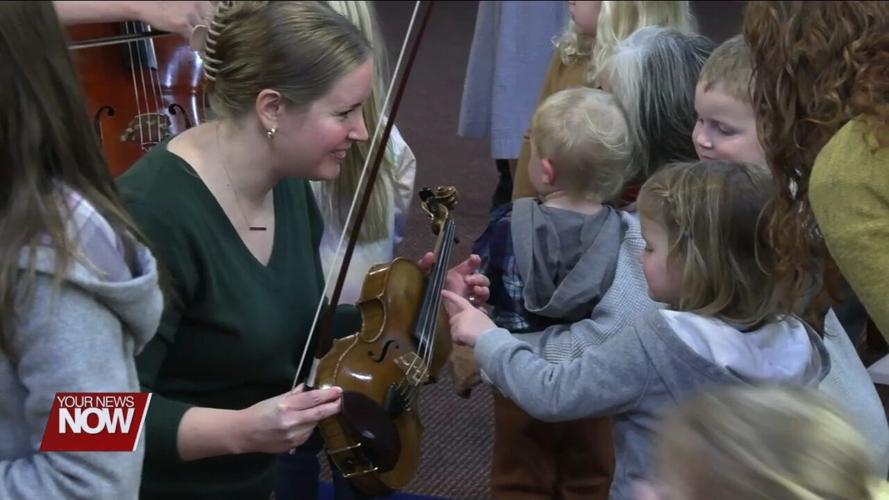 Young children learn about and hear music from string instruments at Symphony Storytime