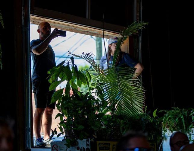 Attendees watch from an open window during former North Carolina Gov. Roy Cooper’s “Make Stuff Cost Less” event at Oklawaha Brewing Company in Hendersonville on Aug. 20, 2026.