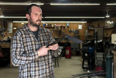 Todd Minoski, of Goathead Knives, checks the form as he shapes heated steel into a knife, Tuesday, March 1, 2022, in his home workshop in Finleyville, Pennsylvania.