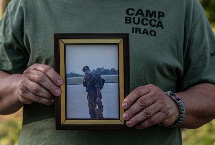 Robert Bucca holds a photo of his brother Ron, an FDNY Fire Marshal and resident of Tuckahoe, N.Y. who died in the Sept. 11 attacks on the World Trade Center. Bucca, photographs July 8, 2026, wears a t-shirt that says Camp Bucca, Iraq, which is a military