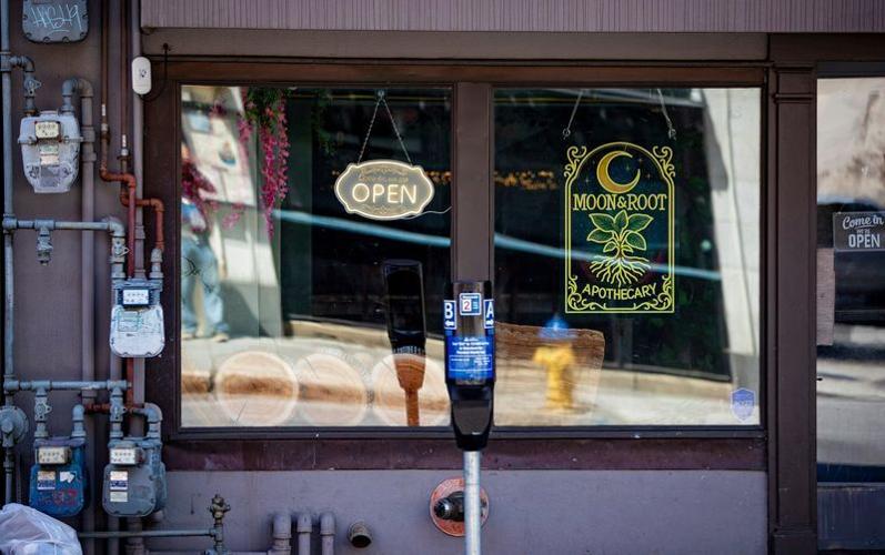A sign hangs in the window of Moon & Root Apothecary along College Street in downtown Asheville on May 13, 2026. The business is owned by Lewis Cantwell.